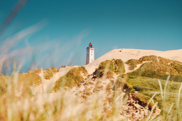 endless sand dunes with the old historic lighthouse Rubjerg Knude in bright summer light. Denmark