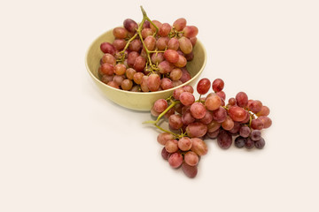 Bowl of red ripe grapes on neutral background