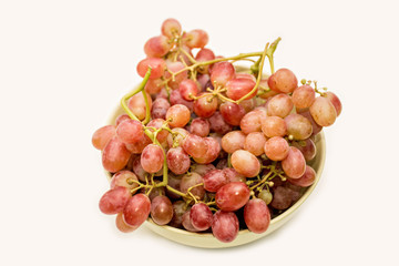 Bowl of red ripe grapes on neutral background