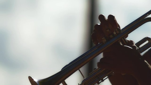 Slow motion close up shot on the hands of a street busker playing the trumpet