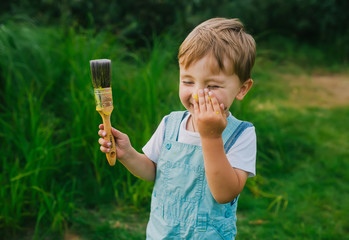 Cheerful and happy little boy with big paintbruch.