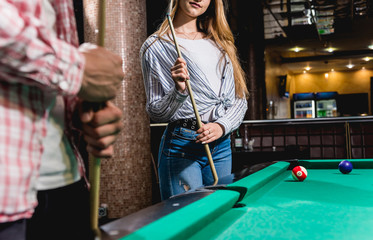 Fototapeta na wymiar Young woman playing in billiard. Posing near the table with a cue in her hands