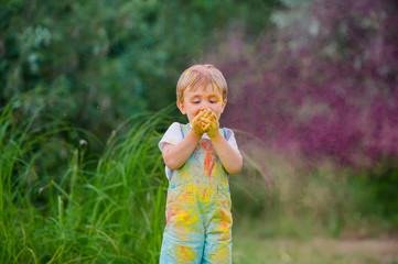 Laughing little boy with paint stained her face outdoors.