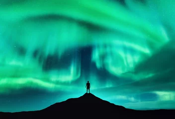 Gordijnen Aurora borealis en silhouet van een man op de bergtop. Lofoten eilanden, Noorwegen. Mooie aurora en man. Alleen reiziger. Hemel met sterren en poollichten. Nachtlandschap met noorderlicht © den-belitsky