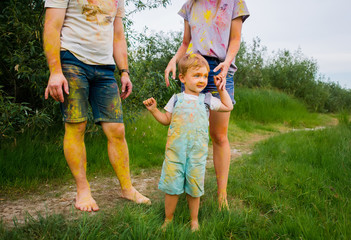 Happy family in multi-colored paints strolling on summer meadow.
