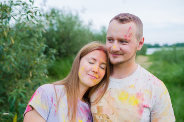 Fototapeta premium Romantic pair in multi-colored paints hugging in summer meadow.