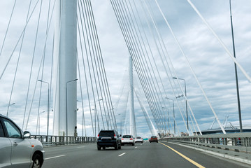 cars on the road on the bridge with metal cables, arch of the bridge