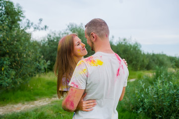 Romantic pair in multi-colored paints hugging in summer meadow.