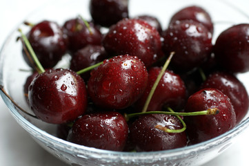 A glass bowl with colourful red wet cherries