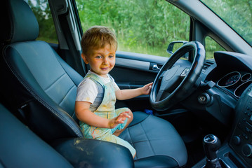 Funny boy with dirty face stained with paint in the car.