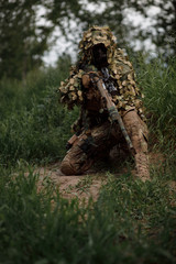Fototapeta na wymiar Airsoft soldier in full ammunition with rifle playing strikeball in outdoor in grass