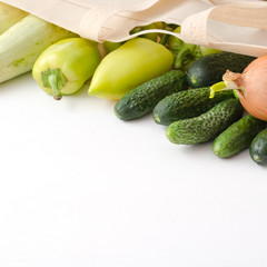 Onion, cucumber, zucchini, pepper in eco bag on white wooden background.
