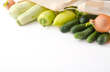 Onion, cucumber, zucchini, pepper in eco bag on white wooden background.