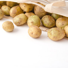 Potatoes in eco bag on white wooden background