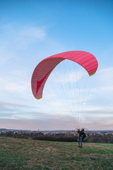 Man holds paraglider taking off in sky under wind