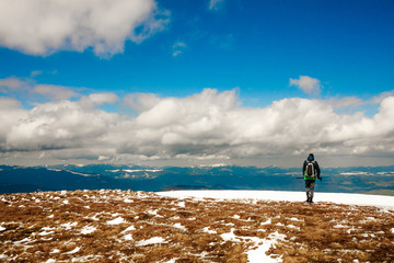 Man looks at the landscape of mountains and clouds.