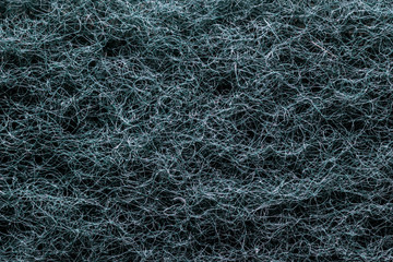 Macro shot of a hard sponge for washing dishes. Furry green wall. A lot of strings mixed up and tangled.