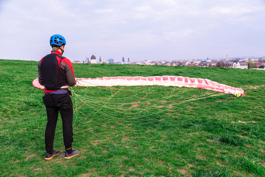 Man with paraplane in green field after landing