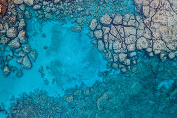 An aerial view of the beautiful Mediterranean Sea, with a rocky shore, where you can see the textured underwater corals and the clean turquoise water of Protaras, Cyprus