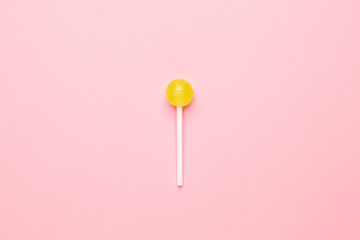 Sweet yellow candy lolipop on pastel pink background.Minimalist composition.