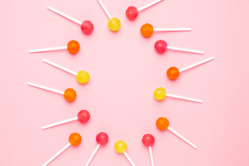 Pink, orange and yellow sweet candy lolipop on a pastel pink background