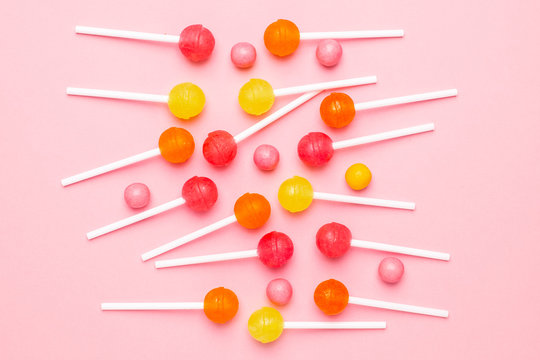 Pink, orange and yellow sweet candy lolipop on a pastel pink background