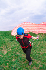 Landed young male skydiver paraglider extinguishes air-filled parachute