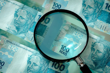 Brazilian money with a magnifying glass, hundred reais banknotes