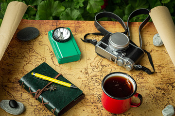 Vacation trip with a map next to a cup of tea and travel equipment, retro style