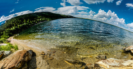 Beautiful mountain lake among mountain ranges and stones green pine forest landscape panoramic