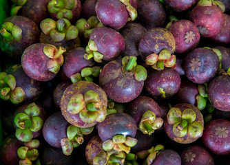 Fresh mangosteen for sale at an outdoor market. Mangosteen piles in one frame. Mangosteen is an Indonesian fruit that has purple skin. Many mangosteen to sell at the markets.