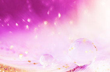 Water drop, transparent bubble and golden glitter on feather background. Beautiful artistic image...