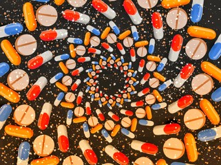 Dark background with medicines, pills and tablets, arranged in concentric circles