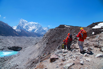 Fototapeta premium Group of tourists with backpacks descends down mountain trail to lake during a way to Everest base camp. Nepal.