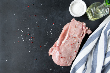 pork tenderloin, raw meat with spices on black background, towel