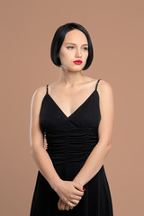 Fototapeta premium Portrait of melancholic lady in dress with straps. Studio shot on beige background