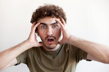 Excited male model exclaims in happiness, doesn`t excpect to recieve pleasant surprise, can`t believe his eyes, gestures actively, expresses great surprisment, isolated over white background