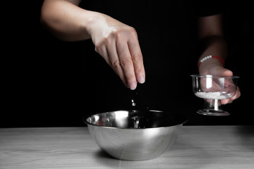 Woman chef sprinkles salt and seasoning for marinated fillet by condiment on a wooden table in the kitchen . Hand sprinkles salt for Preparing healthy food Cooking menu at Home .