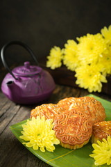 Obraz na płótnie Canvas Mooncakes, teapot, yellow chrysanthemum flowers. Chinese mid-autumn festival food.