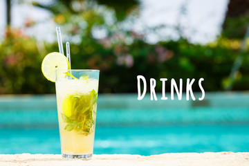 Mojito cocktail at the edge of a resort pool. Concept of luxury vacation. Outdoor pool background. Horizontal. Drinks wording