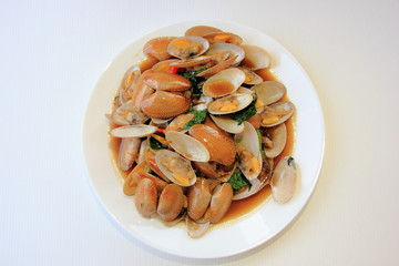 Stir fried clam with chili paste and thai basil leaf in white dish,On the white background, This is thai food cuisine.