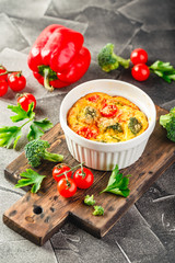 Vegetable frittata with broccoli, red bell pepper and red onion in cast iron skillet. View from above