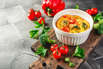 Vegetable frittata with broccoli, red bell pepper and red onion in cast iron skillet. View from above