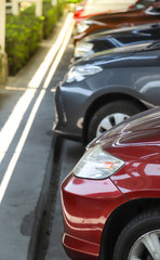 Closeup of front side of red car with  other cars parking in parking lot under roof. vertical view.