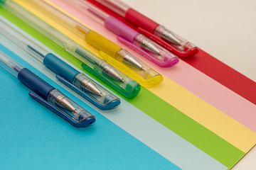 Gel pens forming a rainbow on color paper background