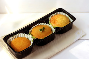 Freshly baked homemade muffins in a black cookie cutter on a wooden table. Top view. Three golden cupcakes in silicone form