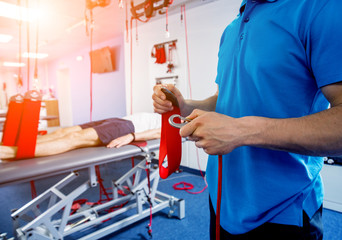 Physiotherapy. Suspension training therapy. Young man doing fitness traction therapy with...