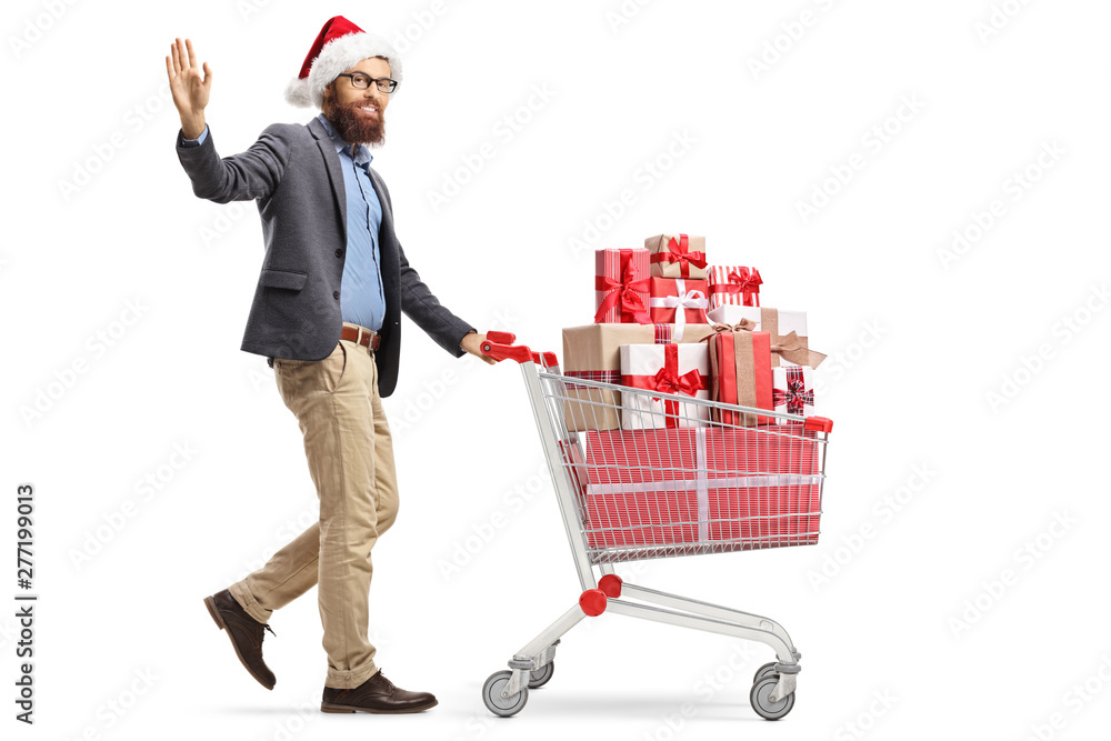 Wall mural Bearded man with a santa claus hat waving and walking with a shopping cart full of christmas presents