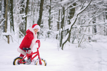 Child dressed  as Santa Claus with gifts in snowy winter outdoors.