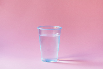 plastic cup of mineral water on pink background